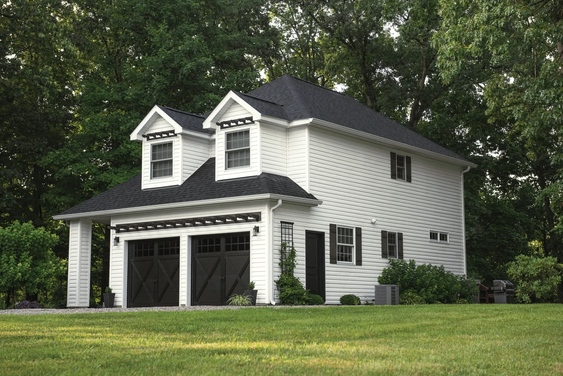 White garage with carriage-style doors on a green lawn